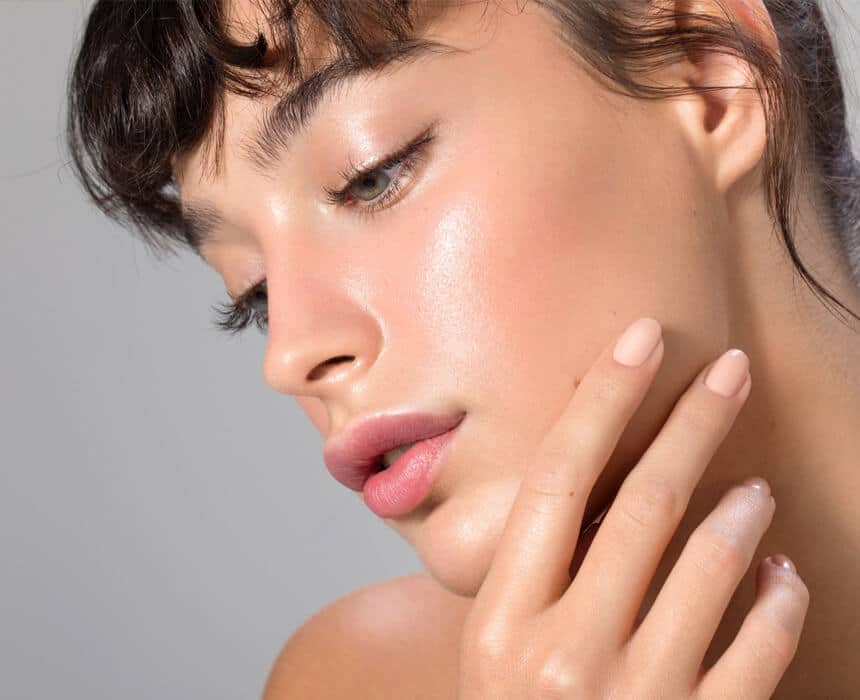 A woman with her hand on her face, considering the results of her recent laser skin treatment session.