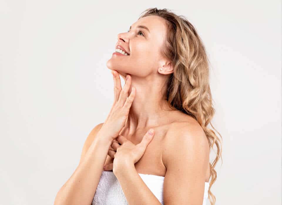 A woman touches her neck, highlighting the effects of Kybella treatment for a refined appearance.