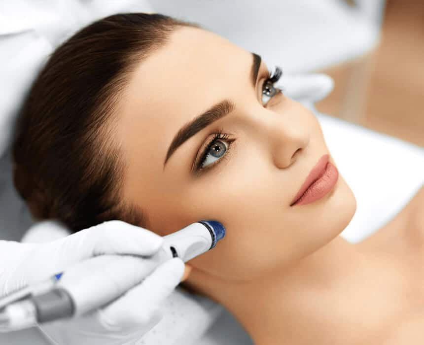 A woman experiencing a microneedling facial treatment with a device, enhancing her skin's appearance in a calming atmosphere.